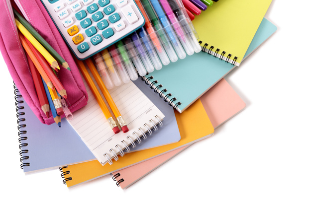 Various school supplies including notebooks, calculator and pink pencil case isolated against a white background